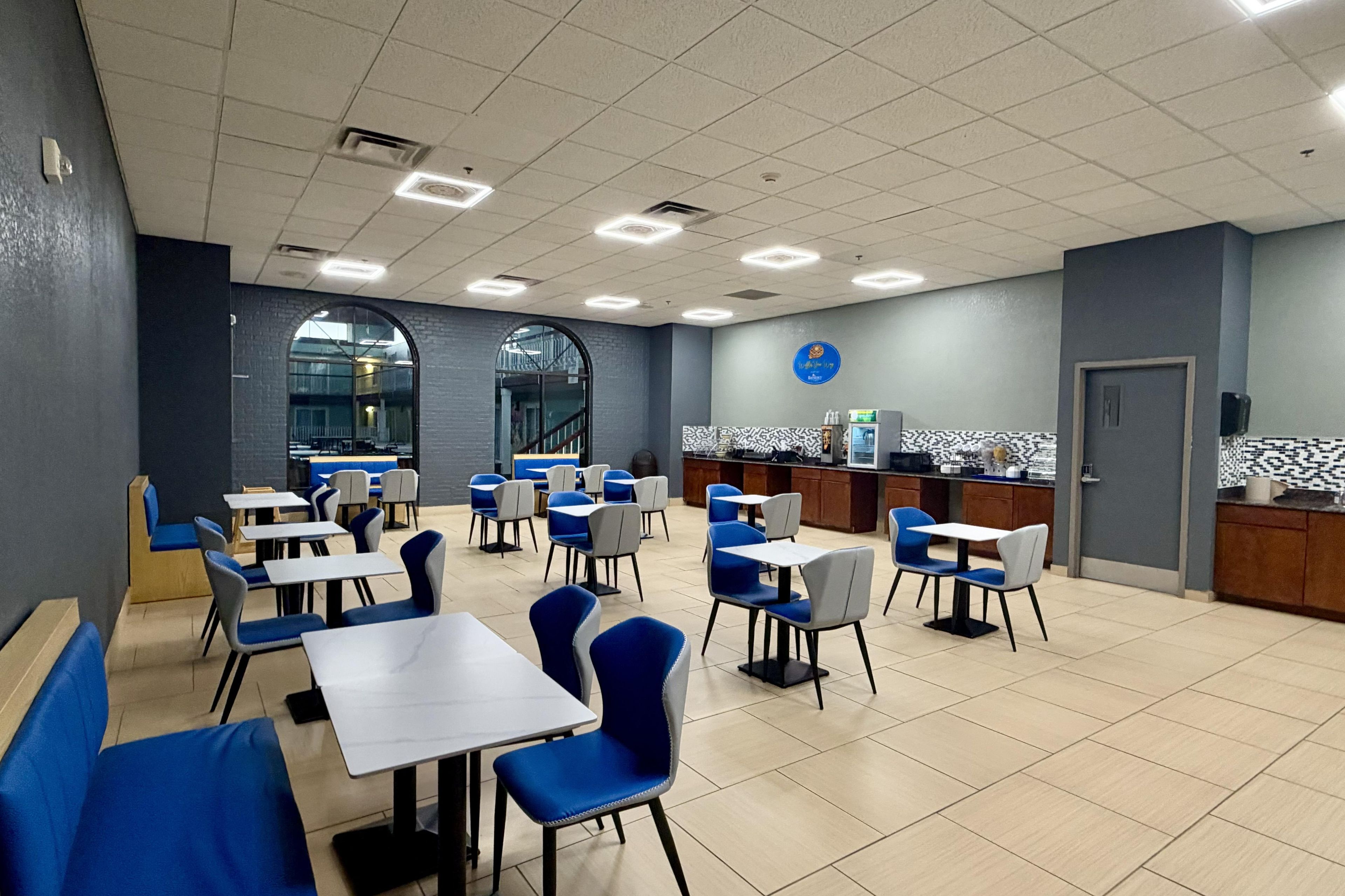 Un restaurante con cabinas y mesas, una zona de cocina y una decoración en tonos azul y blanco.