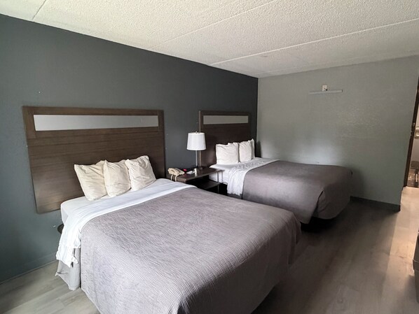 Una habitación de hotel con dos camas, una mesita de noche con lámpara y un teléfono.