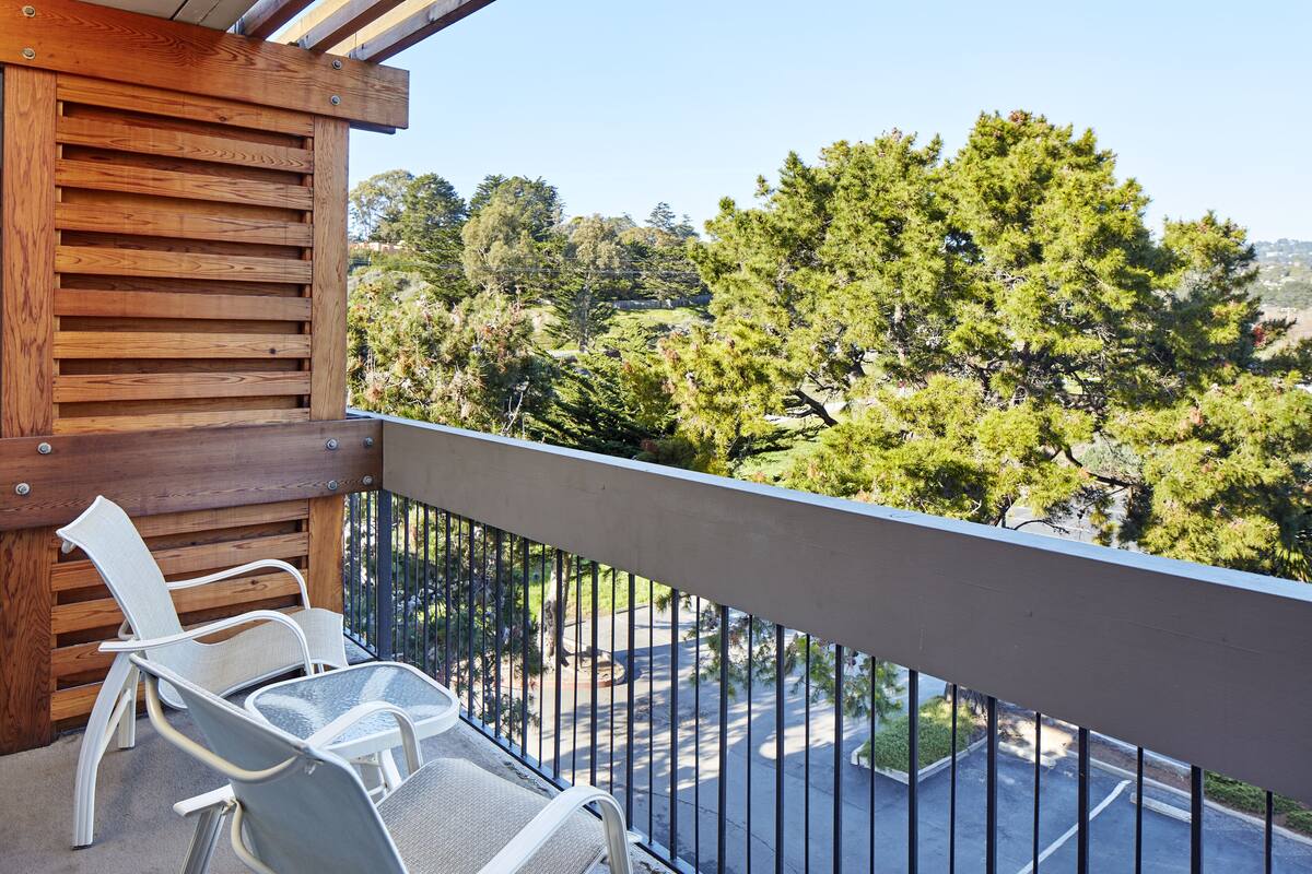 A balcony with a view of a road and trees.