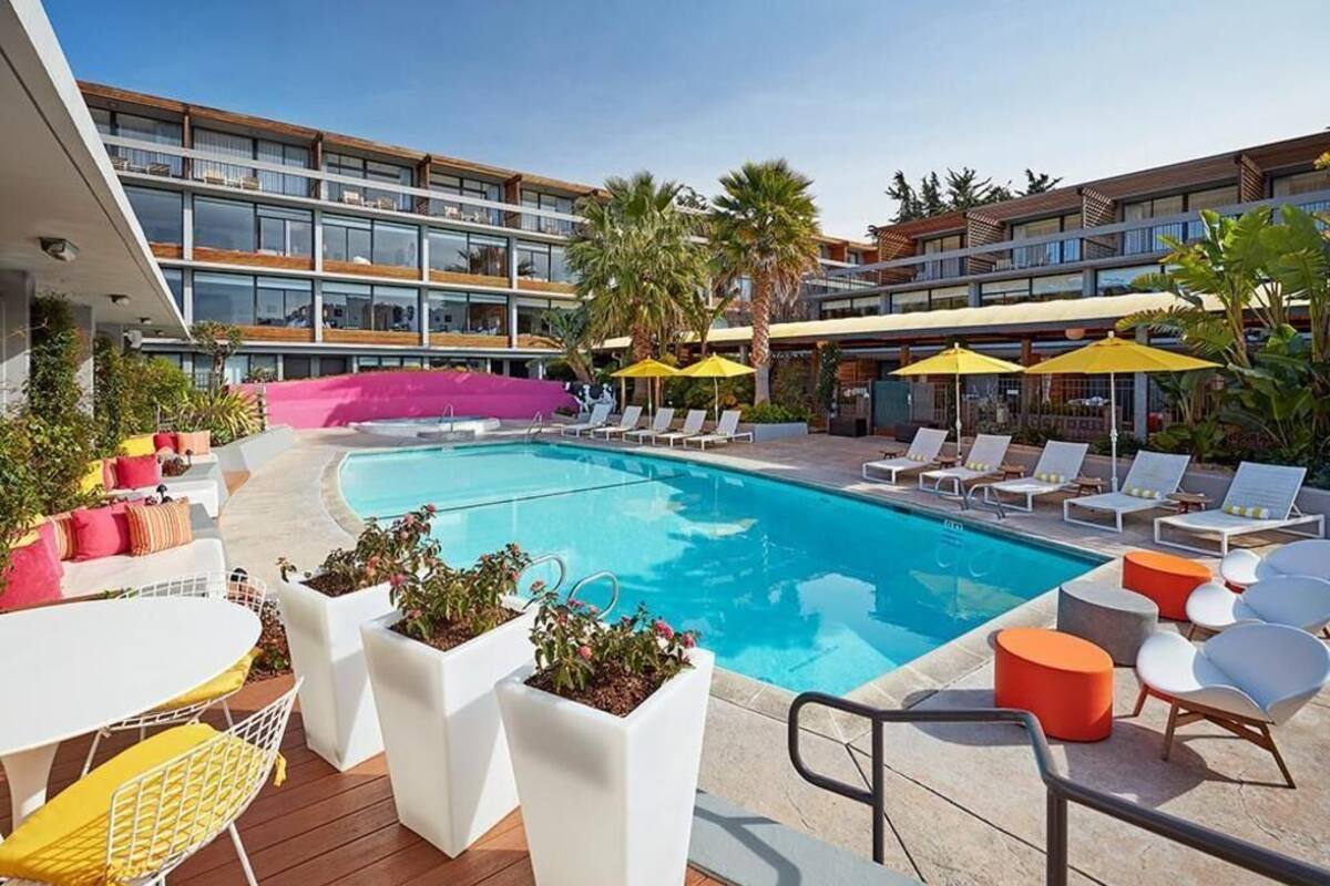 A pool area with lounge chairs, umbrellas, and potted plants.