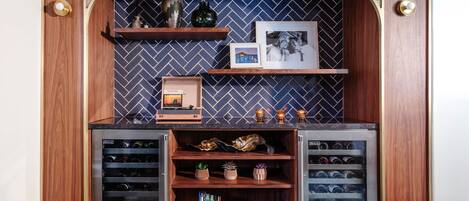 A wine cellar with wooden shelves and a herringbone-patterned wall.