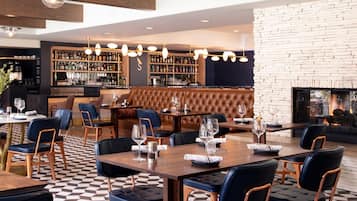 Un restaurante con zona de bar, asientos de cuero y chimenea.