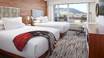 Ein Hotelzimmer mit zwei Betten, einem Schreibtisch und Blick auf die Landschaft.