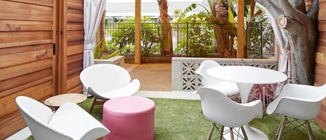 A patio area with a wooden fence, a yellow canopy, and a round table with white chairs.