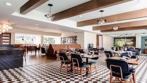 A spacious dining area with a checkered floor, wooden beams, and modern lighting fixtures.