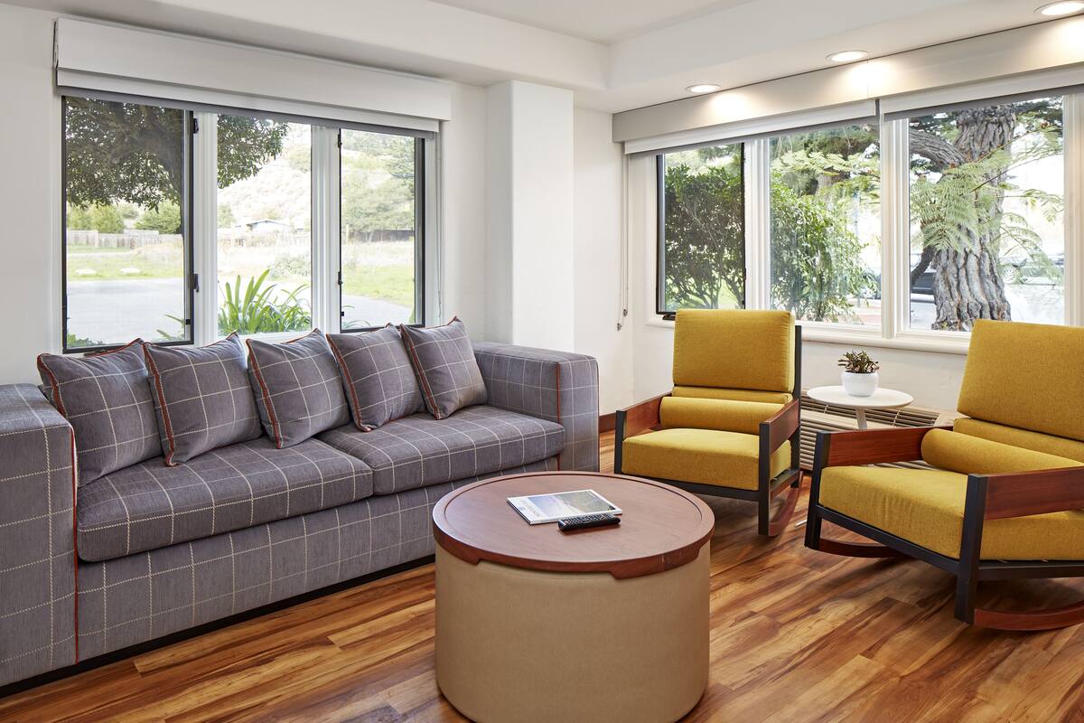 A modern living room with a grey sofa, yellow armchairs, and a round coffee table.