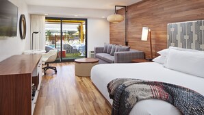 Habitació d'hotel amb un llit gran, un sofà, una taula de treball i vista a l'exterior.