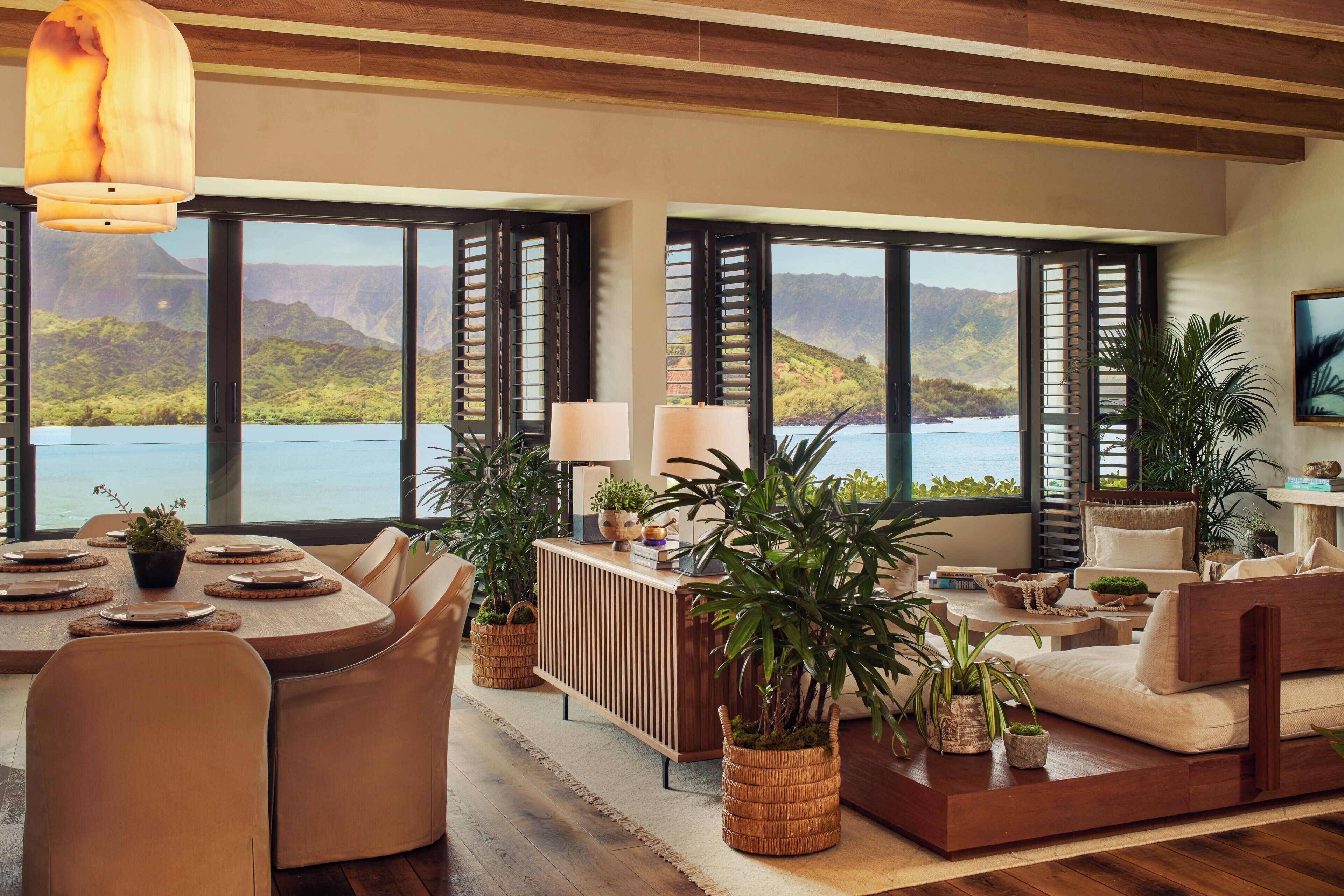 Amplia sala de estar con un gran ventanal con vista a un lago, una mesa de comedor con sillas, y una zona de estar acogedora con un sofá y una mesita auxiliar.