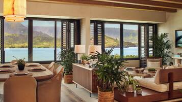 Amplia sala de estar con un gran ventanal con vista a un lago, una mesa de comedor con sillas, y una zona de estar acogedora con un sofá y una mesita auxiliar.