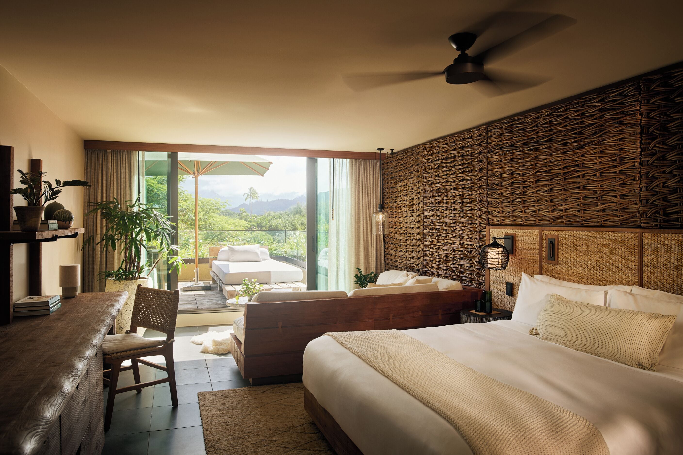 Una habitación de hotel moderna con una cama grande, un escritorio y un balcón con vistas a las montañas.