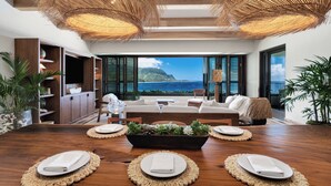 A modern dining area with a wooden table, woven placemats, and a view of the ocean.