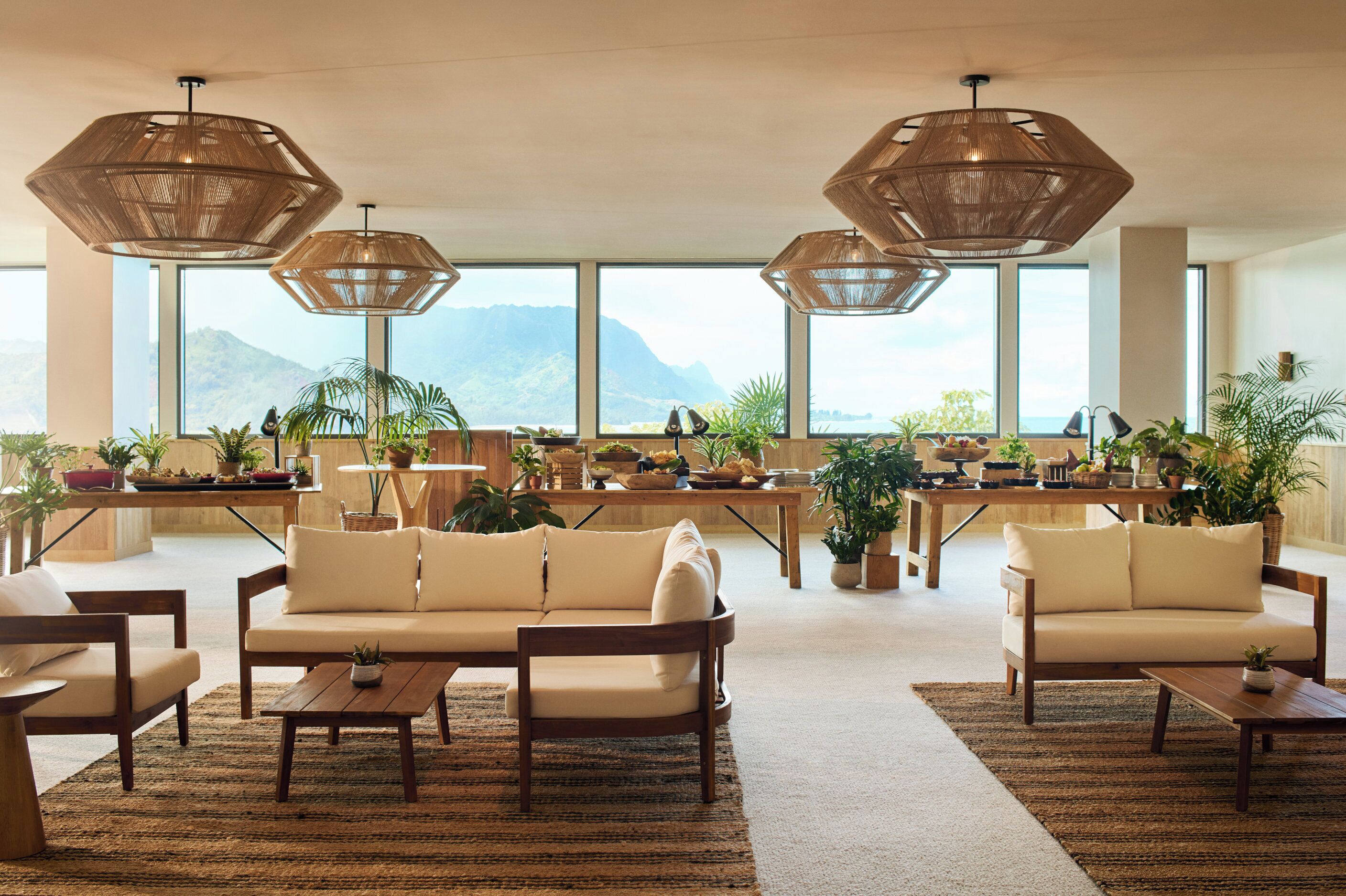 A spacious lounge area with multiple seating options, large windows offering mountain views, and decorative hanging lamps.