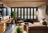 A cozy living area with a wooden ceiling, large windows, a sofa, a coffee table, and a dining table with chairs.