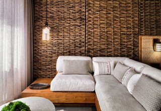 A modern living room with a woven wall, a sofa, a wooden coffee table, and a small side table with a bowl of moss.