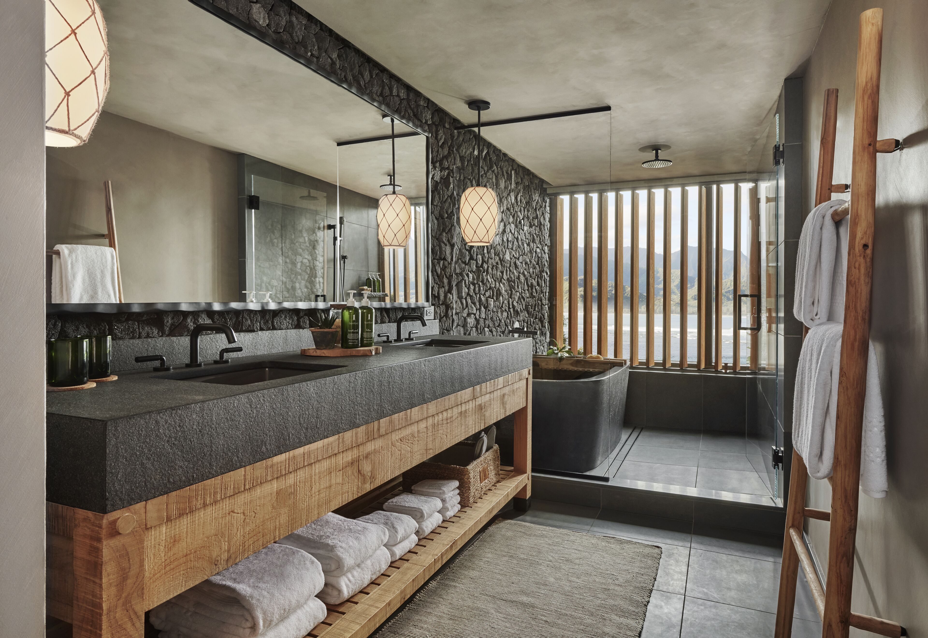 Un baño moderno con un lavamanos grande, tocador de madera y mampara de vidrio.