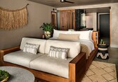 A modern bedroom with a sofa, bed, and a ceiling fan.