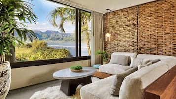 A modern living room with a large window, a sofa, a round coffee table, and a wicker wall panel.
