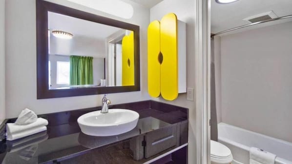 Un baño con un espejo grande, un lavamanos y una bañera.