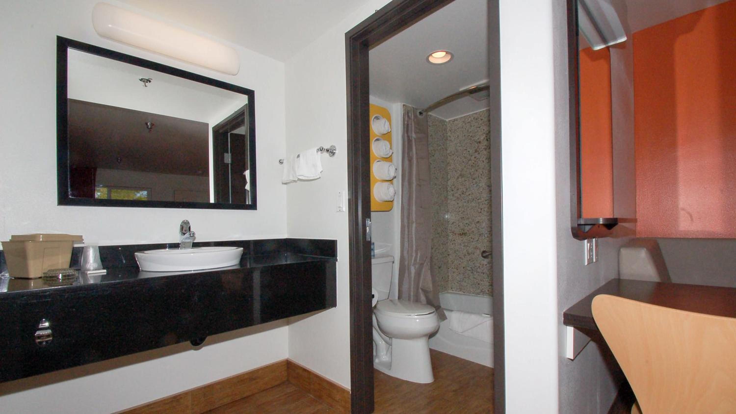 A bathroom with a sink, mirror, toilet, and shower.