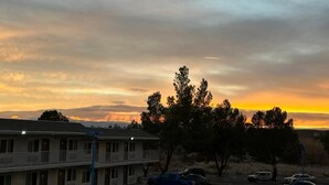 A motel with a two-story structure, a parking lot, and a sunset sky. - Motel 6 Victorville - Desert Express (Victorville)