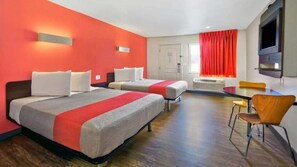 Une chambre d’hôtel avec deux lits, une table à manger et un téléviseur.