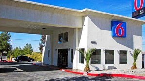 A 6 Motel with a white exterior, large windows, and a red curb. - Motel 6 Victorville - Desert Express (Victorville)