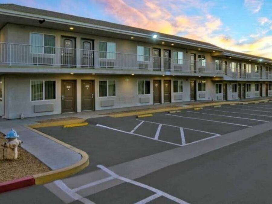 A motel with a two-story structure, a parking lot, and a fire hydrant.