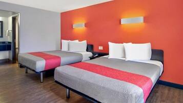 Habitación de hotel con dos camas, una pared de acento roja y suelo de madera.