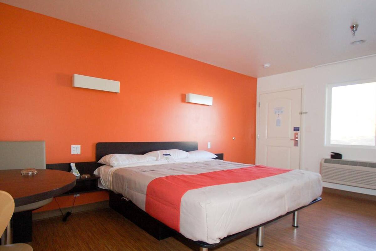 Une chambre d’hôtel avec un lit, un bureau et une chaise.