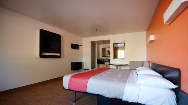 Una habitación de hotel con una cama, televisión, escritorio y espejo.