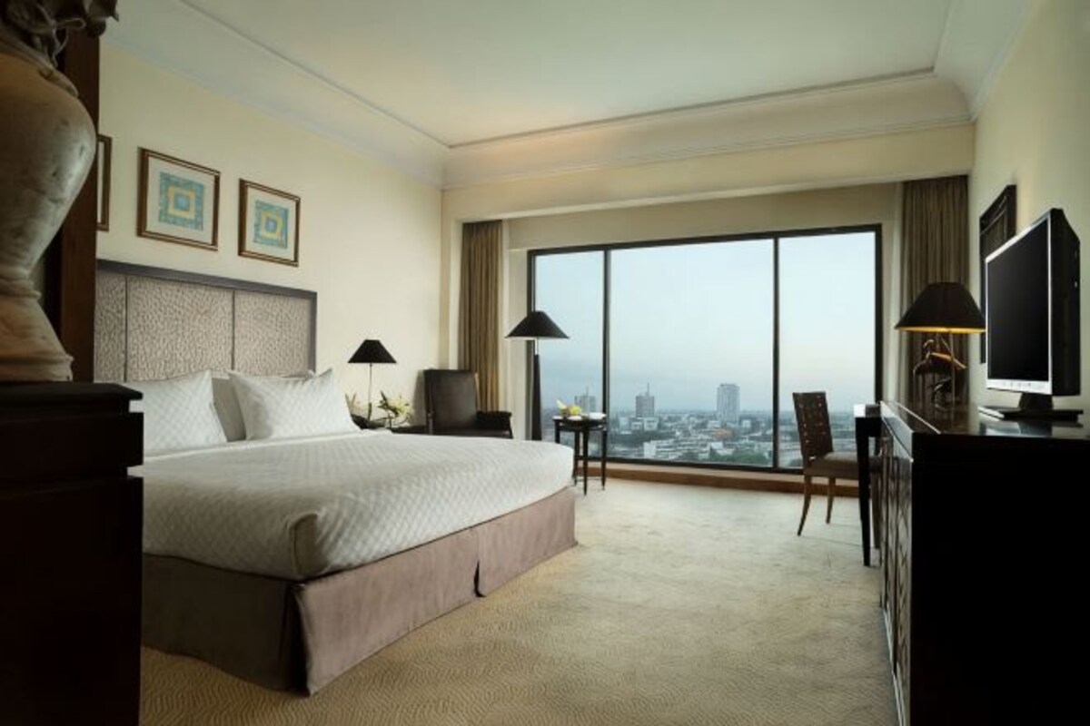 Una habitación de hotel con una cama grande, un escritorio, un televisor y vistas a la ciudad.