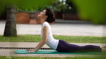 A person performing a yoga pose on a mat outdoors.
