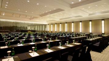 A conference room with rows of tables, chairs, and green bottles, likely for a meeting or event.