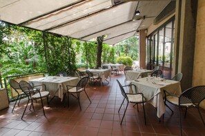 Enjoy a meal under the shade of a white canopy, surrounded by lush greenery and comfortable seating.