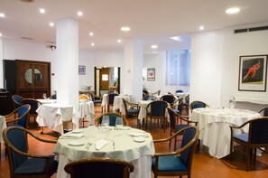 Enjoy meals in a formal dining area with round tables and comfortable seating.