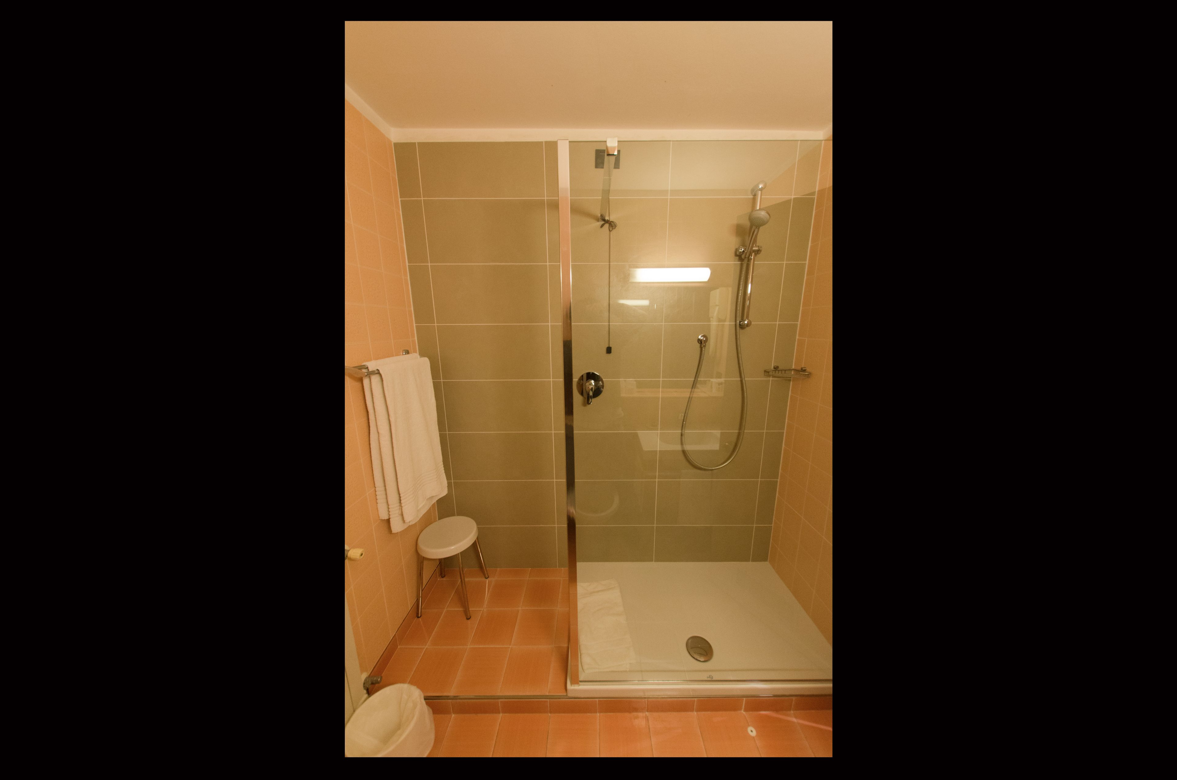 Cabina de ducha con paredes de vidrio, cabezal de ducha de mano y grifo empotrado.