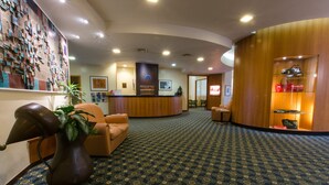 Un hall d’hôtel comprenant un comptoir d’accueil, un espace salon et une vitrine présentant des sacs à main.