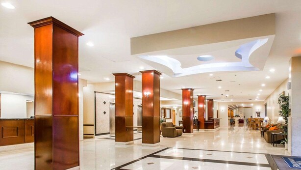 A spacious lobby with high ceilings, polished marble floors, and modern wooden pillars.