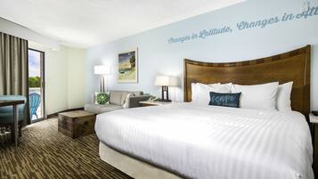 Quarto de hotel com uma cama grande, uma escrivaninha, uma cadeira e vista para o exterior.
