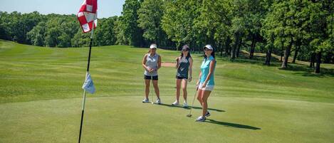 A golf course with three people standing near a flag.