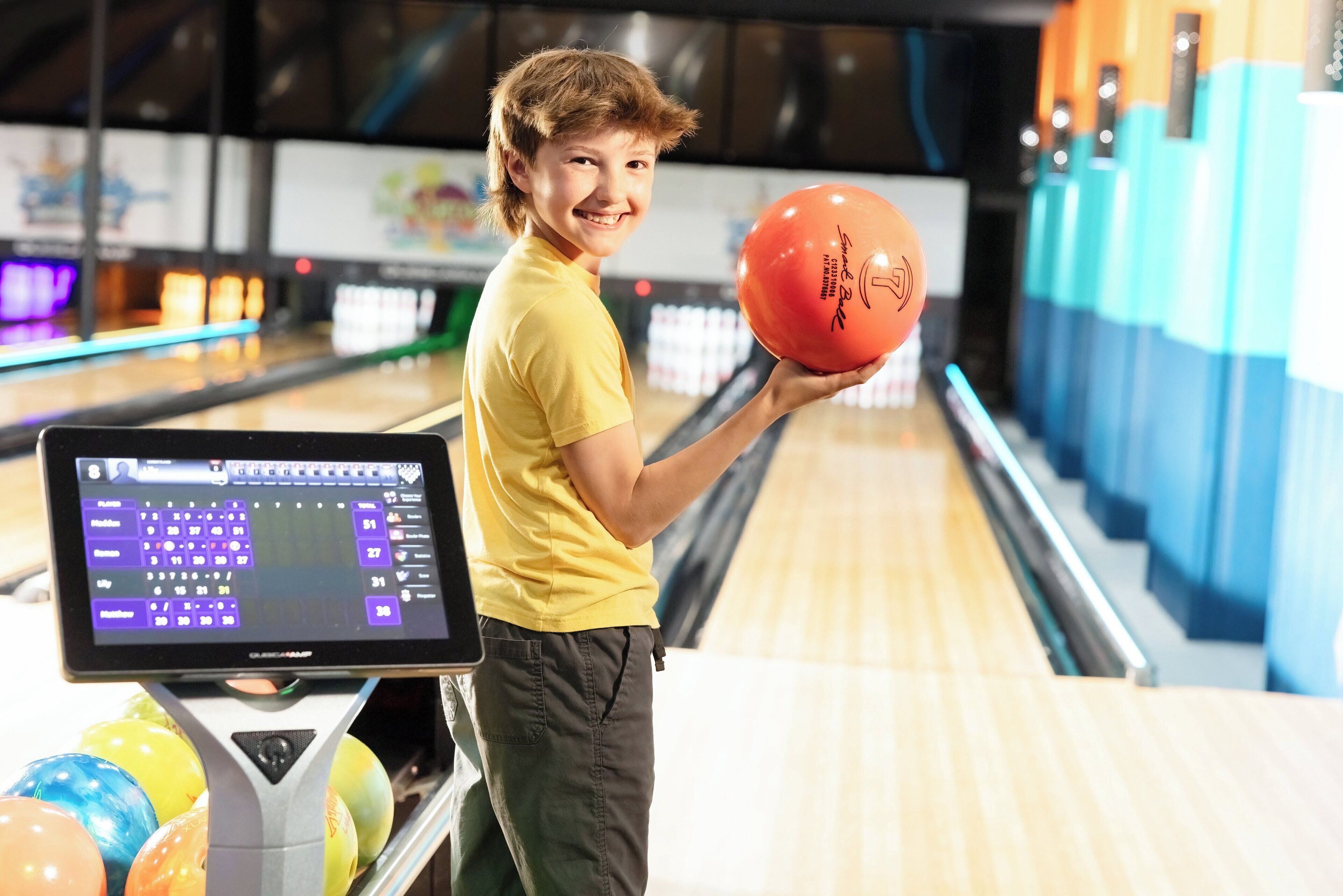A bowling alley with a digital score display and colorful bowling balls.