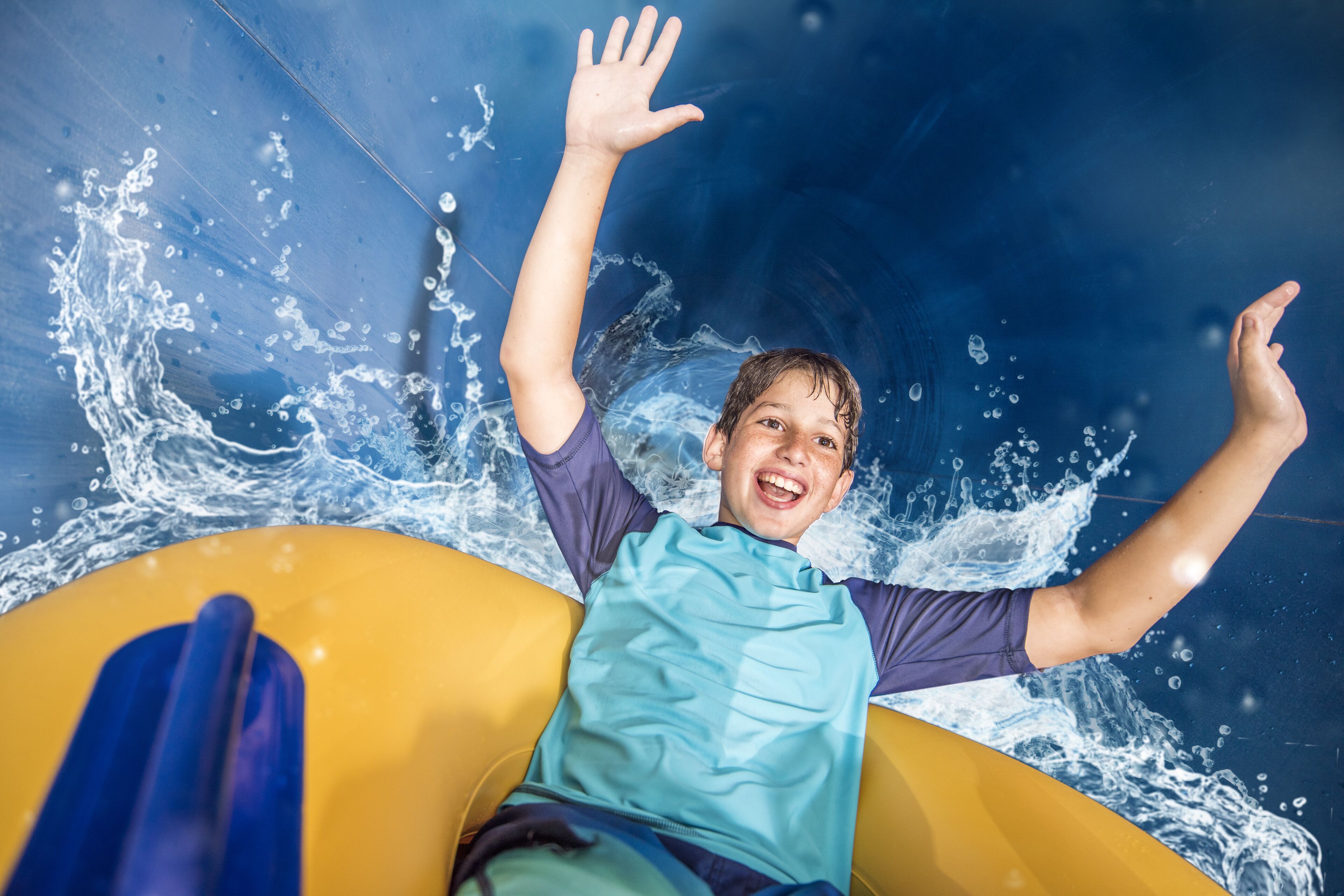 A person on a yellow raft in a water slide.