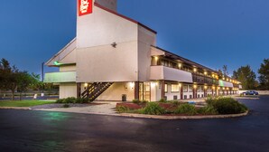 Un hôtel Red Roof, reconnaissable à son grand panneau rouge, doté d’un espace extérieur abrité et d’un parking.