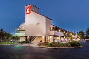 Een Red Roof hotel met een opvallend rood bord, een overdekt buitengebied en een parkeerplaats.