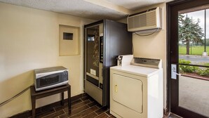 Une petite cuisine équipée d’un four à micro-ondes, d’un petit réfrigérateur et d’un lave-linge.
