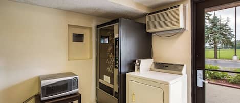 A compact kitchenette with a microwave, a small refrigerator, and a washing machine.