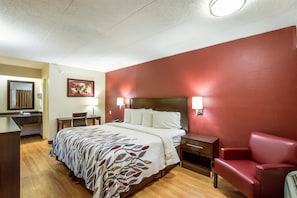 Ein Hotelzimmer mit einem Bett, einem Schreibtisch, einem Stuhl und einer roten Couch.
