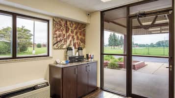 A room with a kitchenette, a large window, and a view of a green landscape.