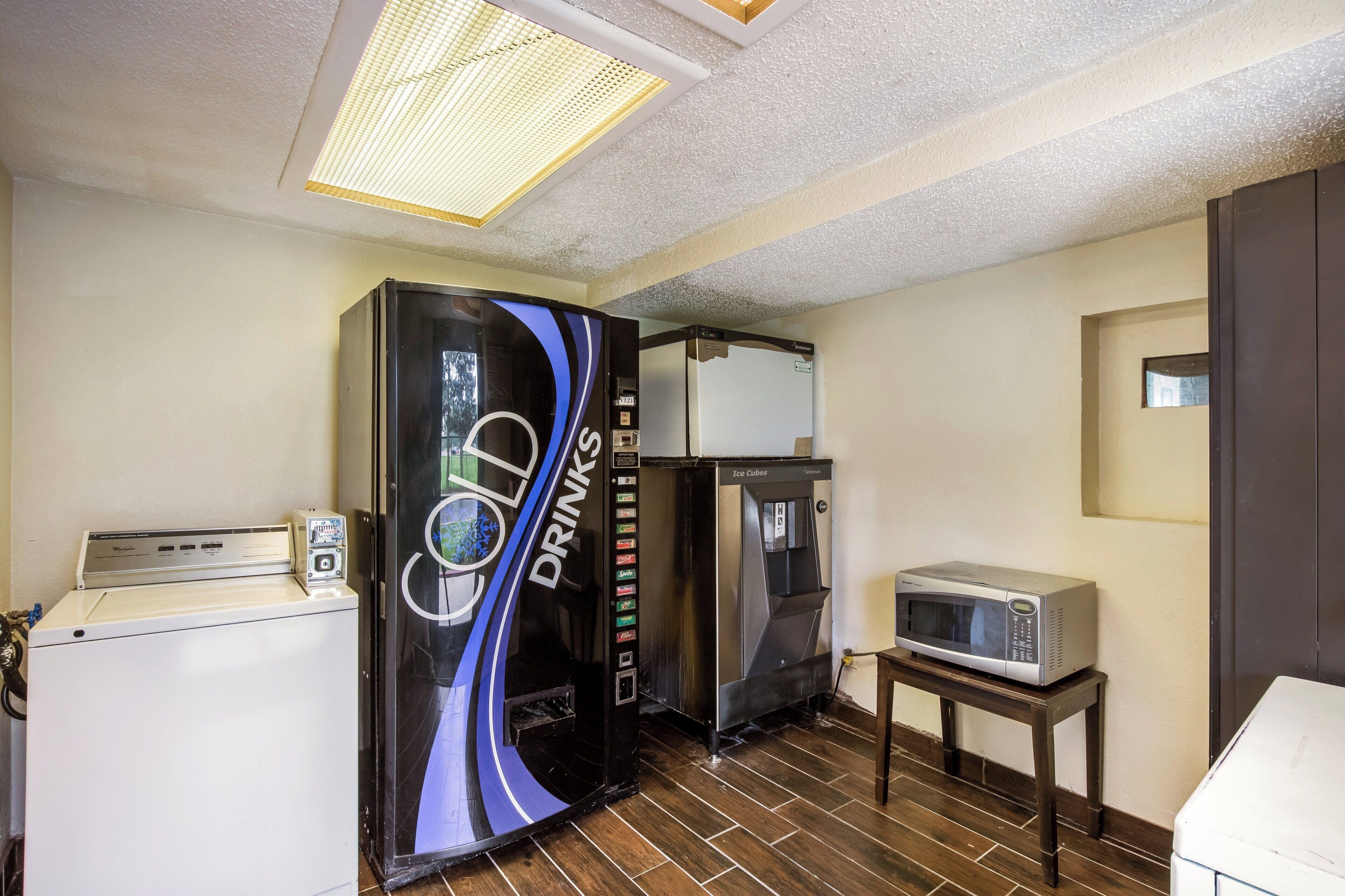 A compact kitchenette with a coffee machine, a beverage dispenser, and a microwave.