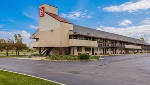 Un hôtel Red Roof Inn avec une structure à deux étages, un espace de stationnement couvert et un jardin aménagé à l’avant.